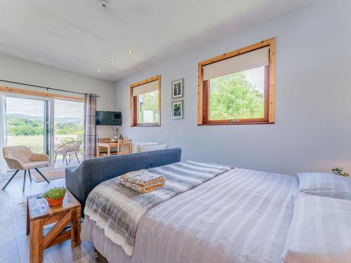 a bedroom with a bed and a couch and windows at Cwtch Enrico - Uk39064 in Scyborycoed