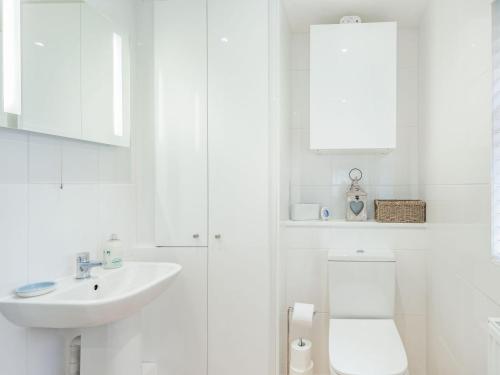 a white bathroom with a sink and a toilet at Tea Pot Cottage in Ringwood