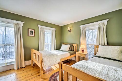 two beds in a room with green walls and windows at Historic Mount Holly Vacation Rental in Hortonville