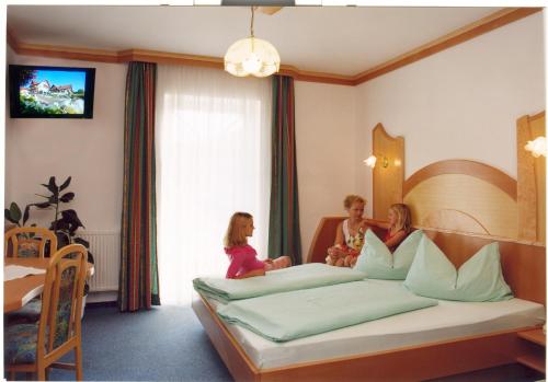 três raparigas sentadas numa cama num quarto de hotel em Pension Gabriele em Unterlamm