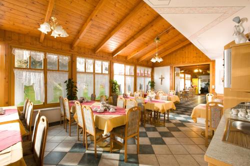 uma sala de jantar com mesas, cadeiras e janelas em Pension Gabriele em Unterlamm