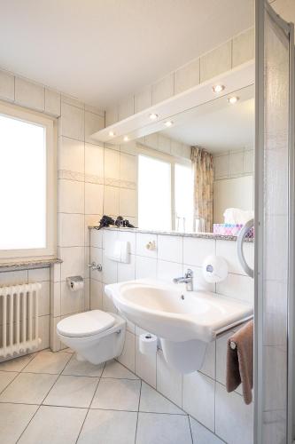a bathroom with a sink and a toilet and a mirror at Hotel Am Steinberg in Hildesheim