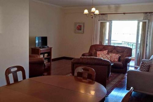 a living room with a table and leather furniture at SeaBreezeBonimar in Funchal
