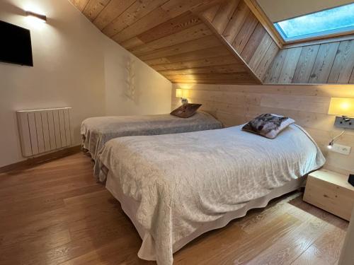 two beds in a room with wooden ceilings at Appartement 201, Duplex avec terrasse et garage in Montgenèvre