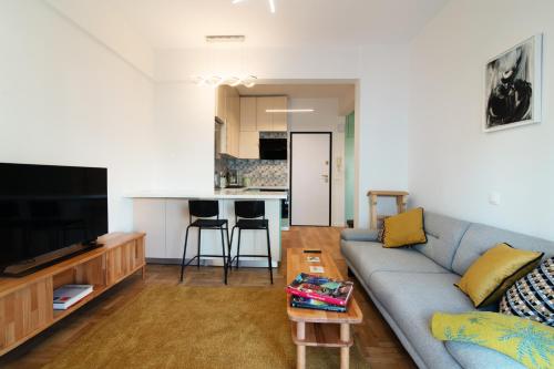 Una sala de estar con un sofá azul y una cocina. en Luxury 1-Bedroom Apartment by the Sea in Athens, en Atenas