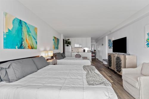 oceanside inn في دايتونا بيتش: غرفة نوم بيضاء مع سرير كبير وأريكة
