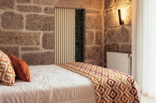 a bed in a room with a stone wall at Casa da Ribeira in Marco de Canavezes