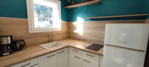 a kitchen with a white refrigerator and a sink at Le Bel Air - Central avec Climatisation & Parking in Gréoux-les-Bains