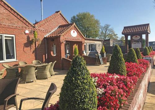 a garden with chairs and flowers in front of a building at Woodthorpe Leisure Park in Strubby