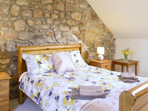 a bedroom with a bed and a stone wall at The Granary - Uk5676 in Boʼness