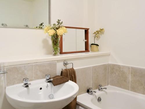 a bathroom with two sinks and a vase of flowers at The Granary - Uk5676 in Boʼness