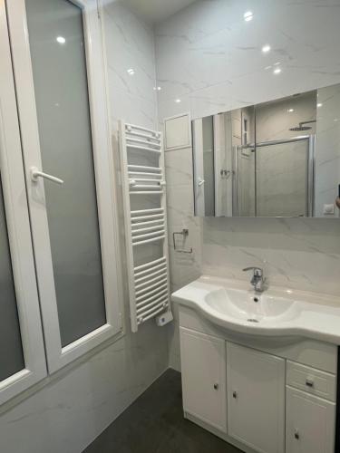 une salle de bain blanche avec un lavabo et un miroir dans l'établissement RESIDENCE NATION, à Paris