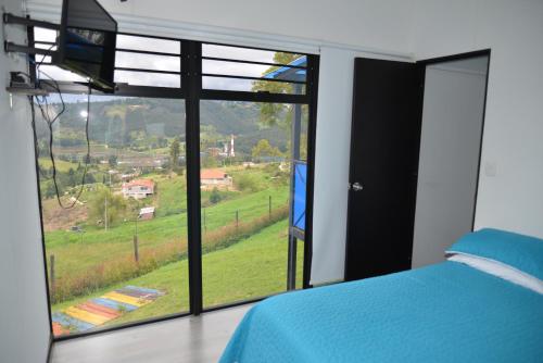 um quarto com uma cama e uma grande janela em CABAÑAS SALEKA Paipa 
