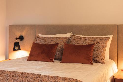 a bed with brown and white pillows on it at Casa da Ribeira in Marco de Canavezes
