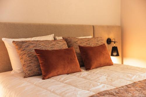 a bed with brown and white pillows on it at Casa da Ribeira in Marco de Canavezes