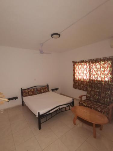 a bedroom with a bed and a chair and a window at TRANQUIL RESORT HOTEL in Brusubi
