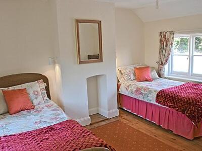 StiffkeyにあるForge Cottageのベッドルーム1室(ベッド2台、壁掛け鏡付)