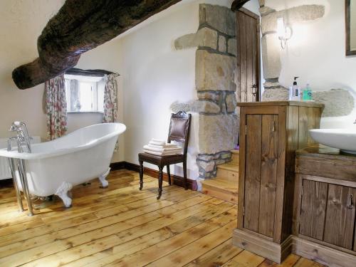 a bathroom with a bath tub and a stone wall at Far View Cottage in Haworth