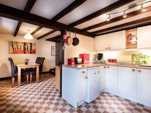 a kitchen with white cabinets and a table in it at Pitts Cottage in Brancaster