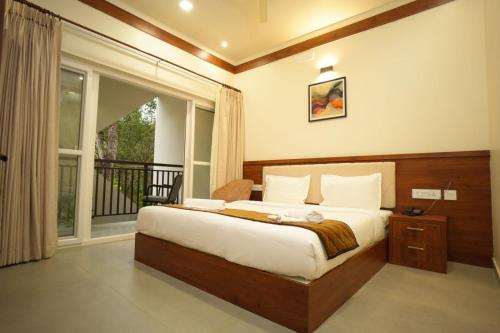 a bedroom with a bed and a large window at Royalton Residency in Mundakāyam