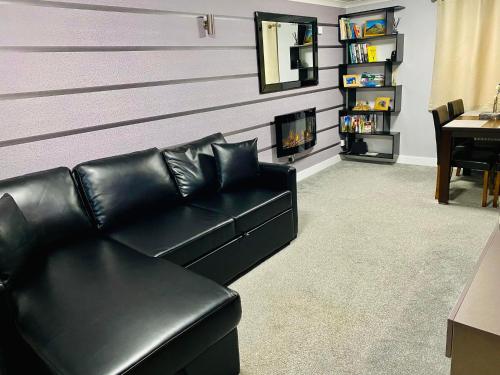 a black leather couch in a living room with a fireplace at Skye View Cottage in Portree