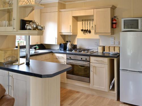 a kitchen with wooden cabinets and a white refrigerator at The Elms - E4306 in Brough