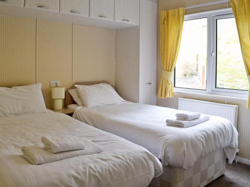 two beds in a room with yellow curtains at The Elms - E4306 in Brough