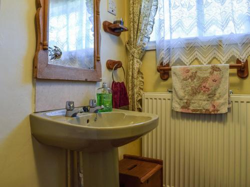 uma casa de banho com um lavatório, um espelho e uma janela em Tudor Cottage em Bidford