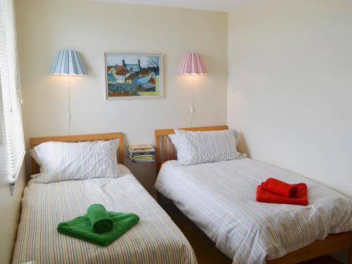 2 camas en una habitación con toallas verdes y rojas en Brierdene End Cottage, en Hartley