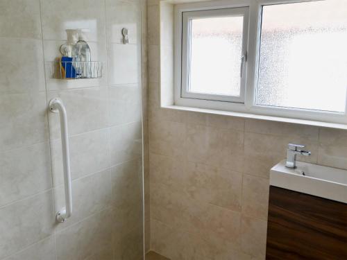 baño con ducha, lavabo y ventana en Brierdene End Cottage, en Hartley