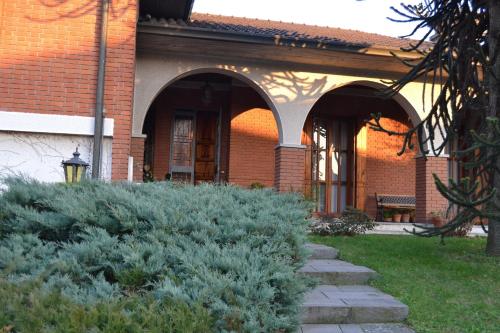 un edificio de ladrillo con arcos y plantas delante de él en La Filanda B&B en Casorezzo