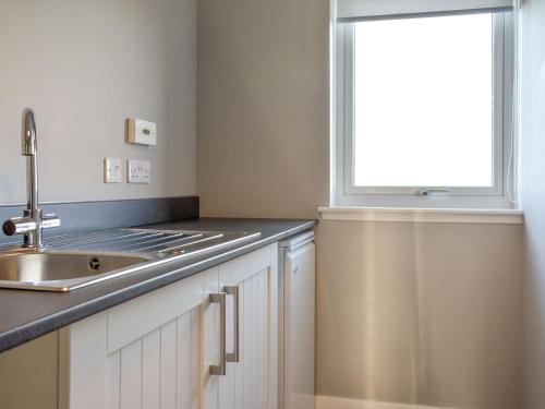 a kitchen with a sink and a window at Benwells Holiday Cottage in Maud