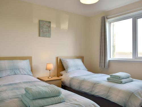 two beds in a small room with a window at Benwells Holiday Cottage in Maud