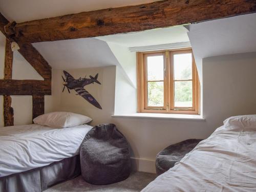 a bedroom with two beds and a window at Lower Goytre Farmhouse in Llanvair Waterdine