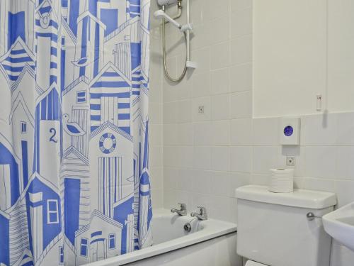 a bathroom with a blue and white shower curtain at Bluebell - 28864 in Stokeinteignhead