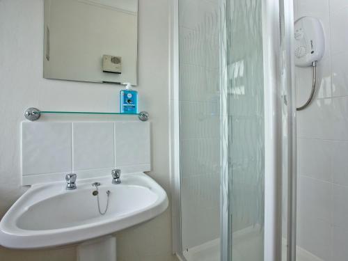 a white bathroom with a sink and a shower at Courts View in Newton Abbot