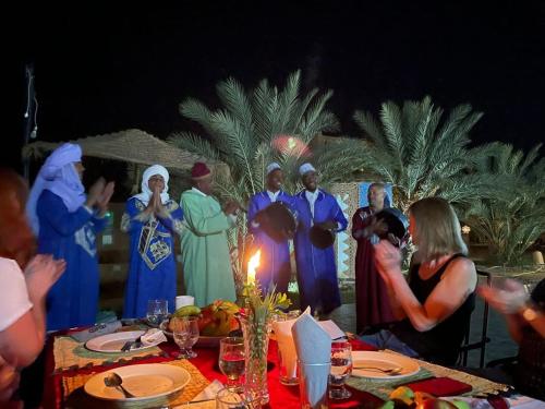 a group of people standing in front of a table at Oasis Tilogui in Zagora