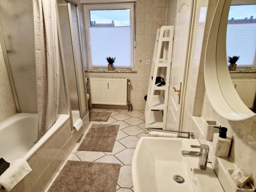 ein Badezimmer mit einem Waschbecken, einer Badewanne und einem Spiegel in der Unterkunft Hofgarten Apartments in Aschaffenburg
