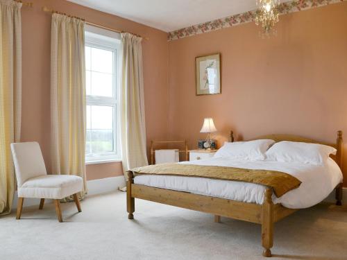 een slaapkamer met een bed, een stoel en een raam bij Forda Farm in Black Torrington