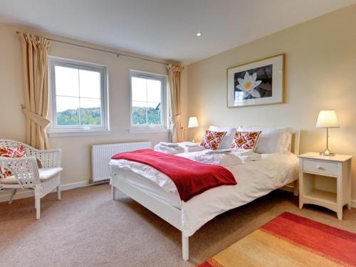 1 dormitorio con 1 cama, 1 silla y 2 ventanas en Osprey Cottage- 27939, en Cambusbarron