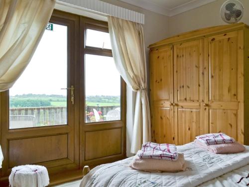 Woodend Bungalow في Hucknall under Huthwaite: غرفة نوم بسرير ونافذة كبيرة