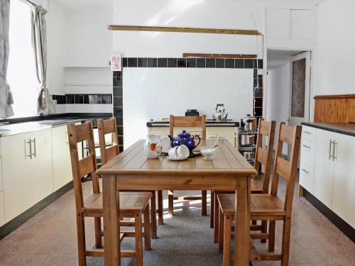 a kitchen with a wooden table and wooden chairs at Ford Farmhouse in Carew