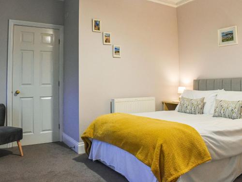 a bedroom with a bed with a yellow blanket on it at Baileys Retreat in Sneaton
