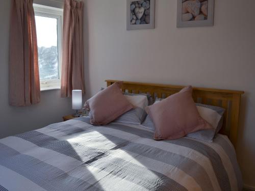 una camera da letto con un letto con cuscini rosa e una finestra di Spring Tides a Beadnell