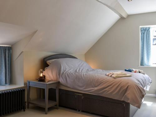 een slaapkamer met een bed en een nachtkastje naast een raam bij Glimsters Cottage in Kentisbeare