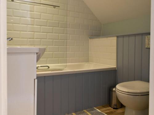 a bathroom with a bath tub and a toilet at Glimsters Cottage in Kentisbeare