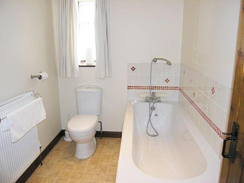ein Badezimmer mit einem WC und einer Badewanne in der Unterkunft Oak Tree Cottage in Gillamoor
