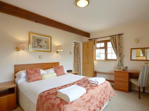 a bedroom with a large bed and a desk at The Hay Barn in Sidbury