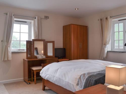 a bedroom with a bed and a desk and a mirror at Aprils Cottage in Kilkhampton
