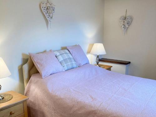 - une chambre avec un lit avec des draps violets et 2 lampes dans l'établissement Swaledale Cottag, à Caldbeck